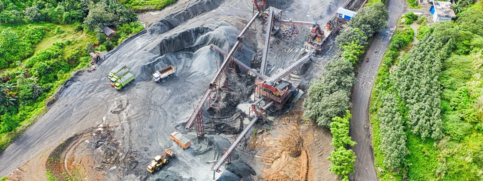 Aerial view of a mining site with tipper trucks, a wheel loader and processing plant