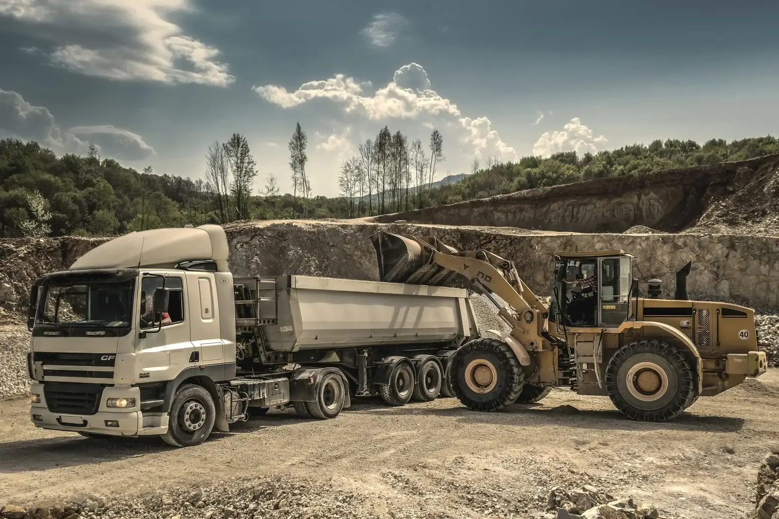 A wheel loader charging a tipper truck on a quarry floor